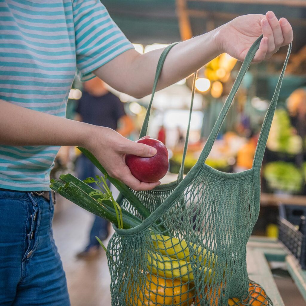 woman buying produce with mesh bag