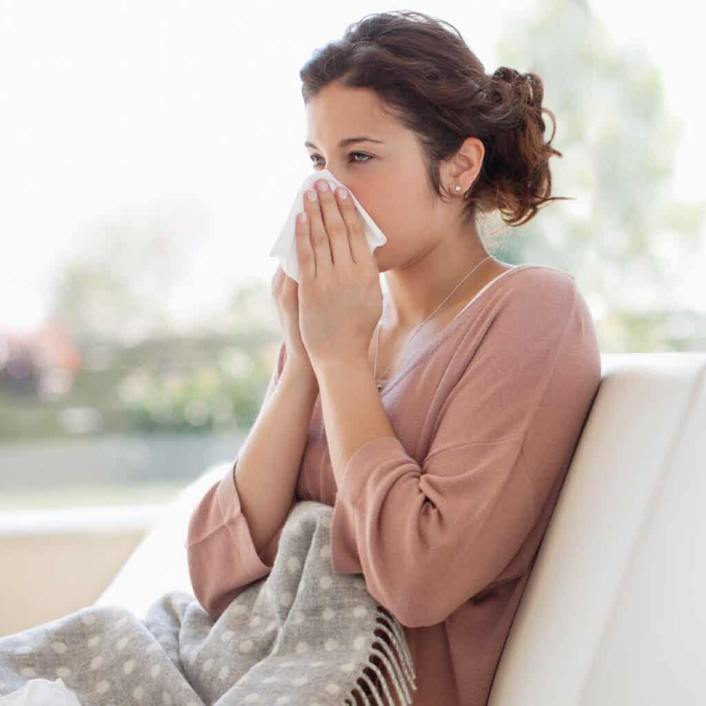 woman with allergies blowing her nose