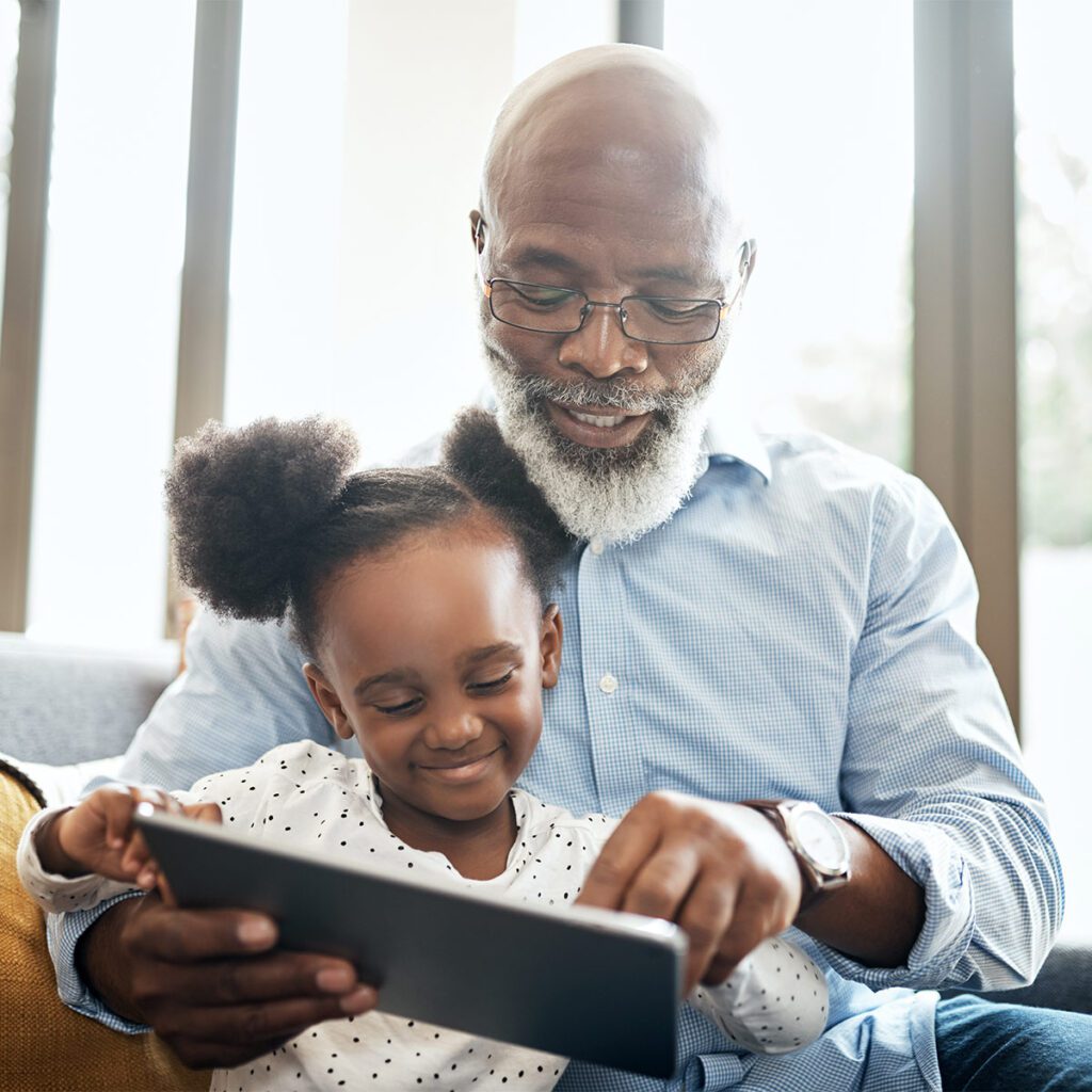 grandfather bonding with his granddaughter with an ipad