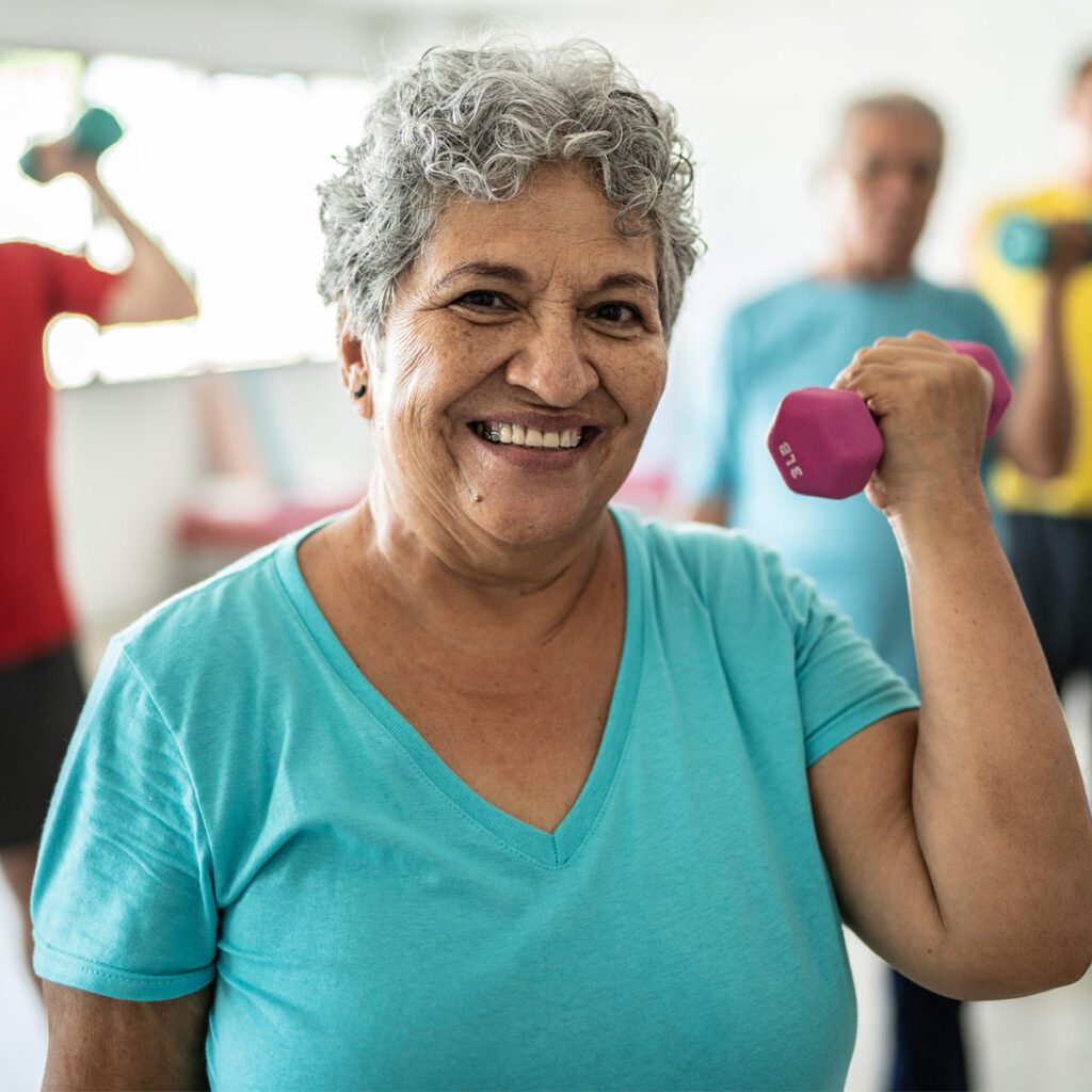 smiling elderly lady doing bicep curls with a weight