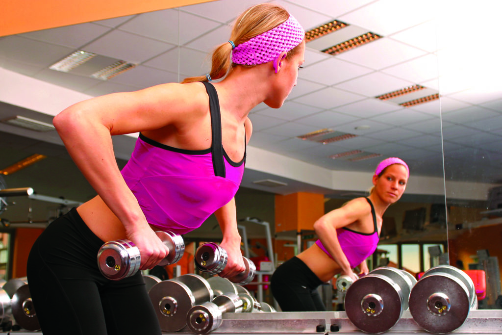 woman pulling up weights in the gym