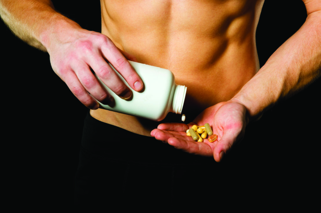 athletic man pouring a large amount of supplements of a pill bottle