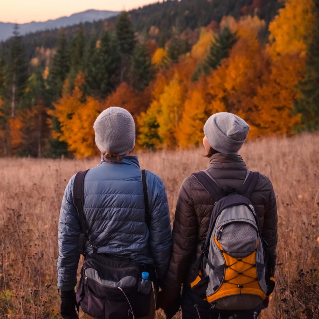 Happy couple feel freedom and enjoy the beautiful autumn forest in the mountains and looking together on sunset