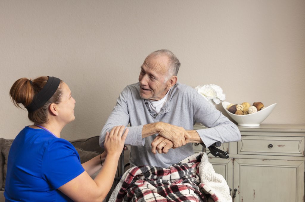 A female nurse caring for an elderly man at his home.