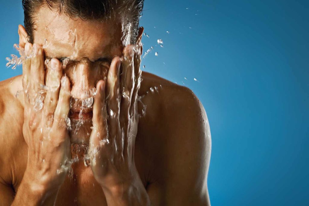 man splashing water on his face
