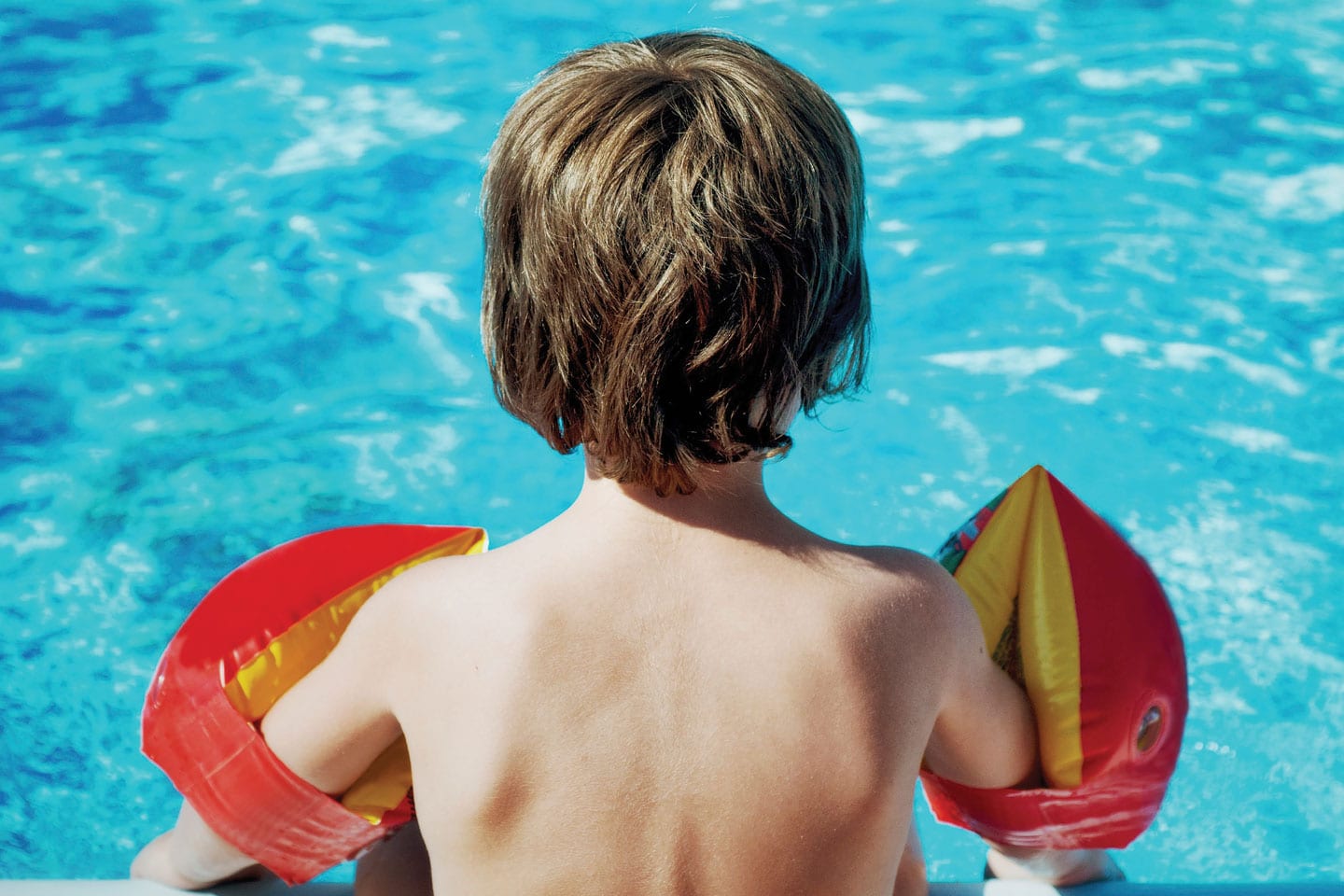 Child with floaties in swimming pool