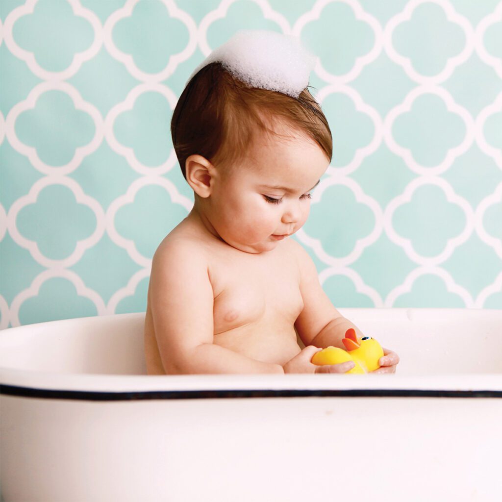 baby in bathtub with soap on top of head