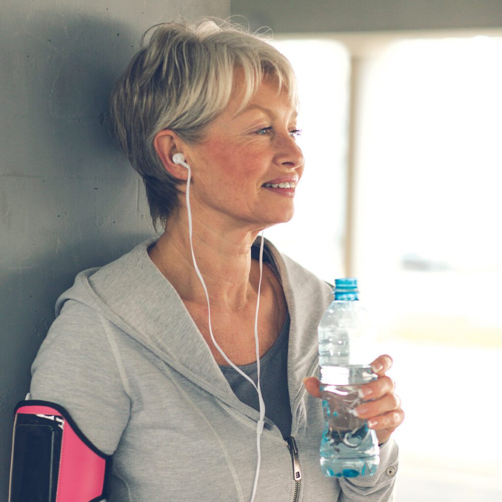 elderly woman drinking water after workout