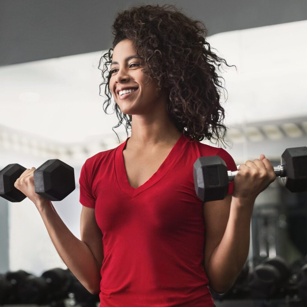 African-american fitness woman doing biceps workouts with dumbbells in gym, copy space