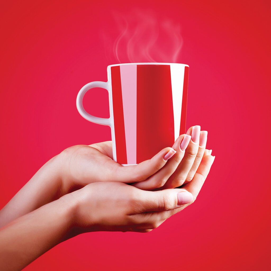 two hands holding a hot red mug in red background