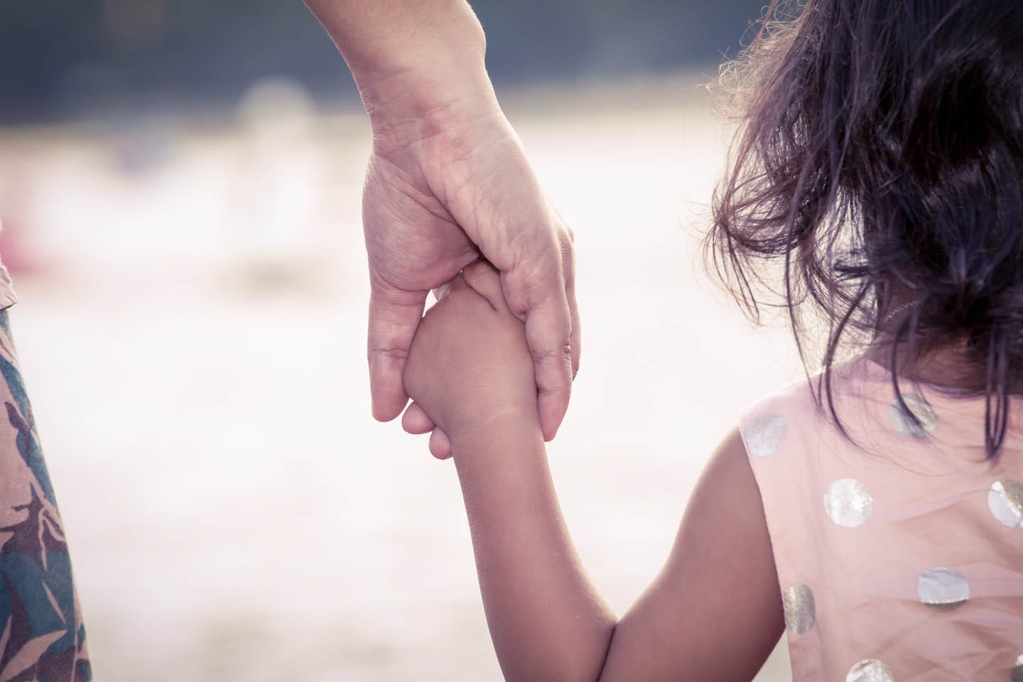 Parent holding the hand of young daughter