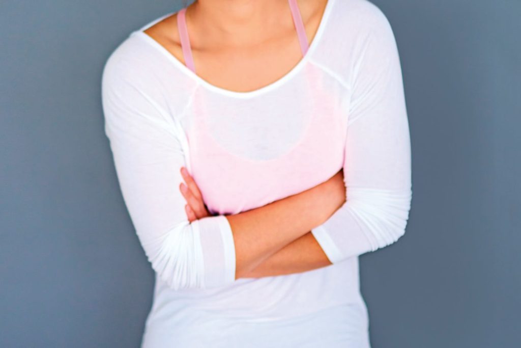 Woman in pink sports bra with white pullover and gray leggings with arm crossed in chattanooga