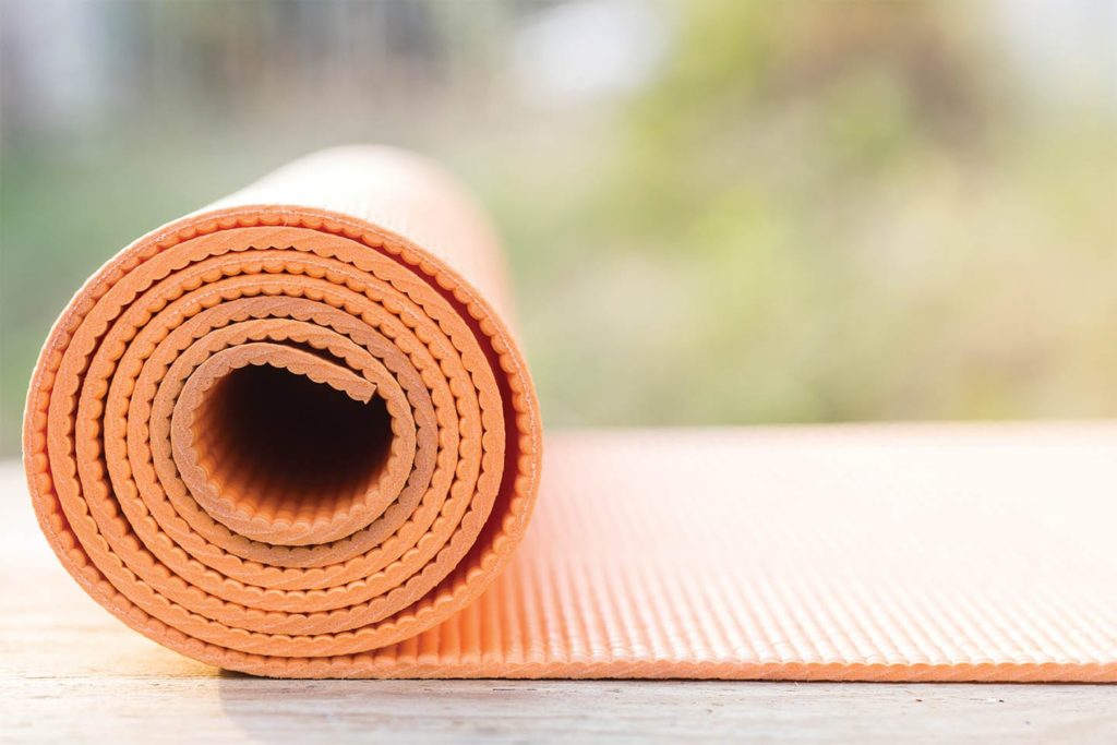 orange yoga mat being unrolled outside in chattanooga