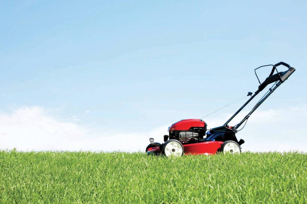 red push lawn mower with green grass and blue sky in chattanooga