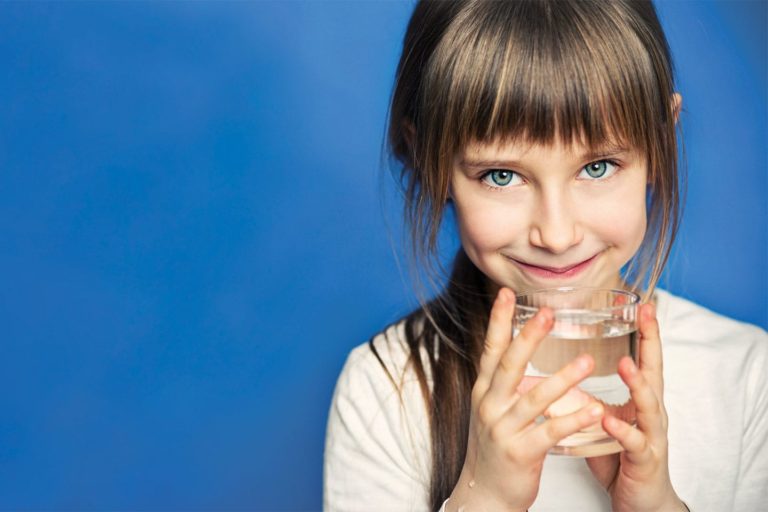 little girl drinking a glass of water on a blue background in chattanooga