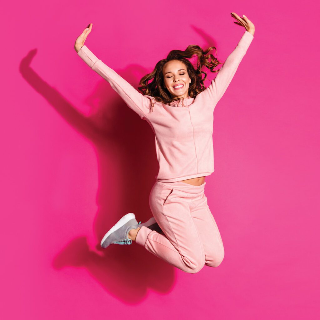 happy woman jumping in pink altheisure sweatsuit with joggers and zip up hoodie in chattanooga