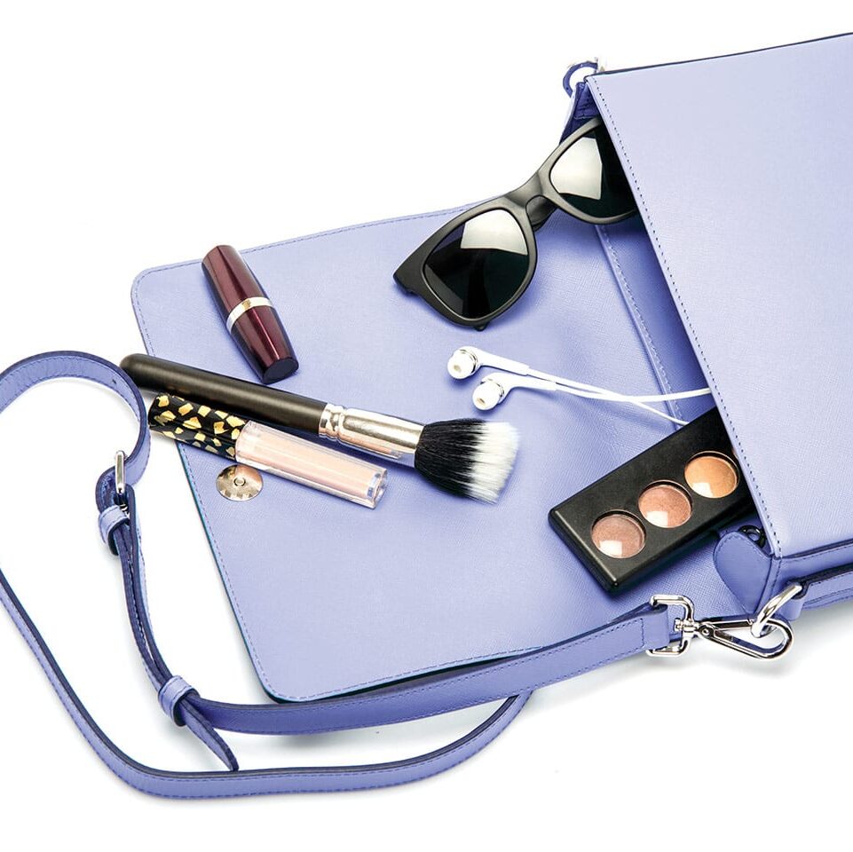 purple purse with makeup sunglasses and earbuds spilling out how to organize your bag