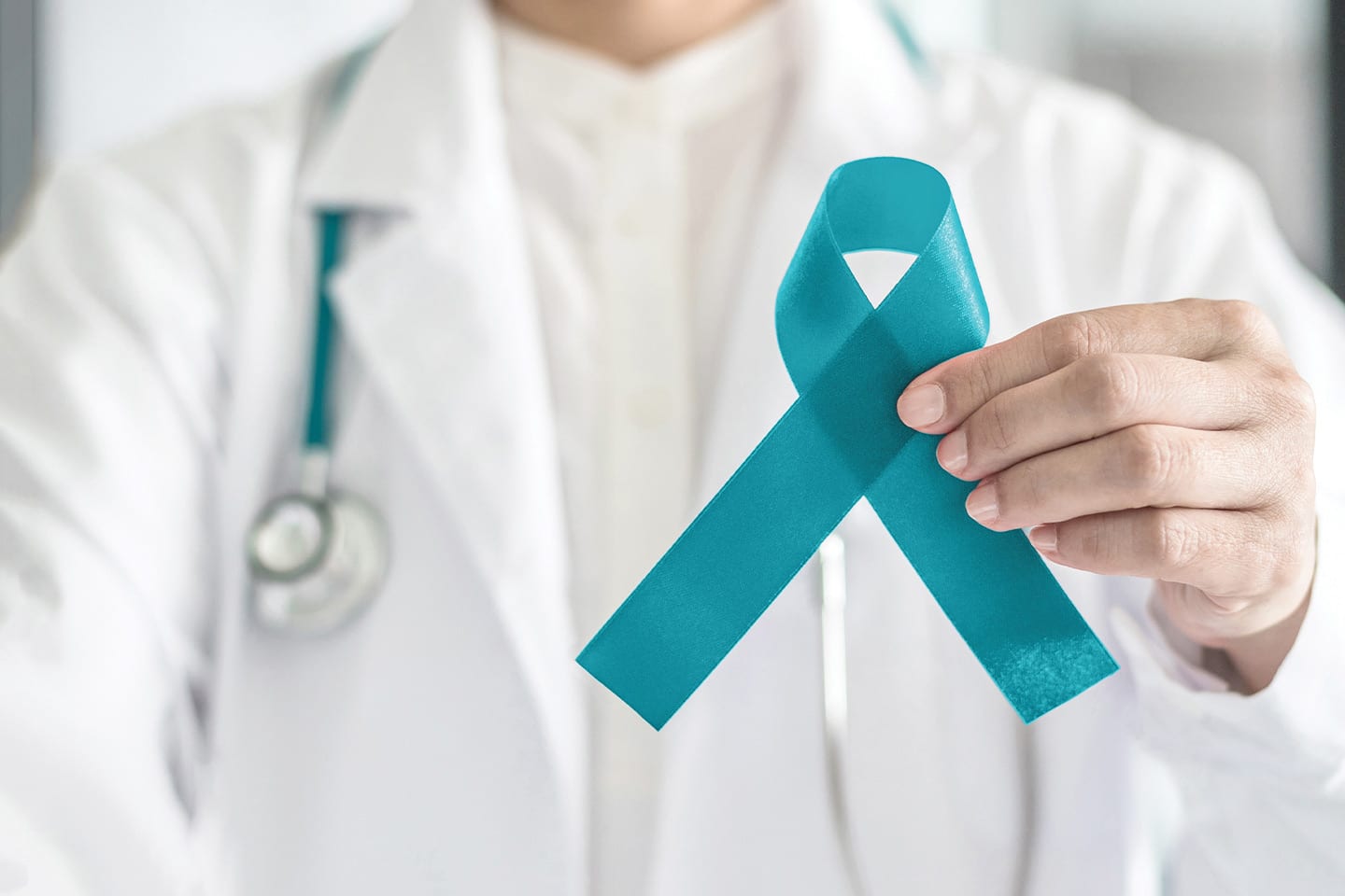 doctor holding a teal ribbon for ovarian cancer