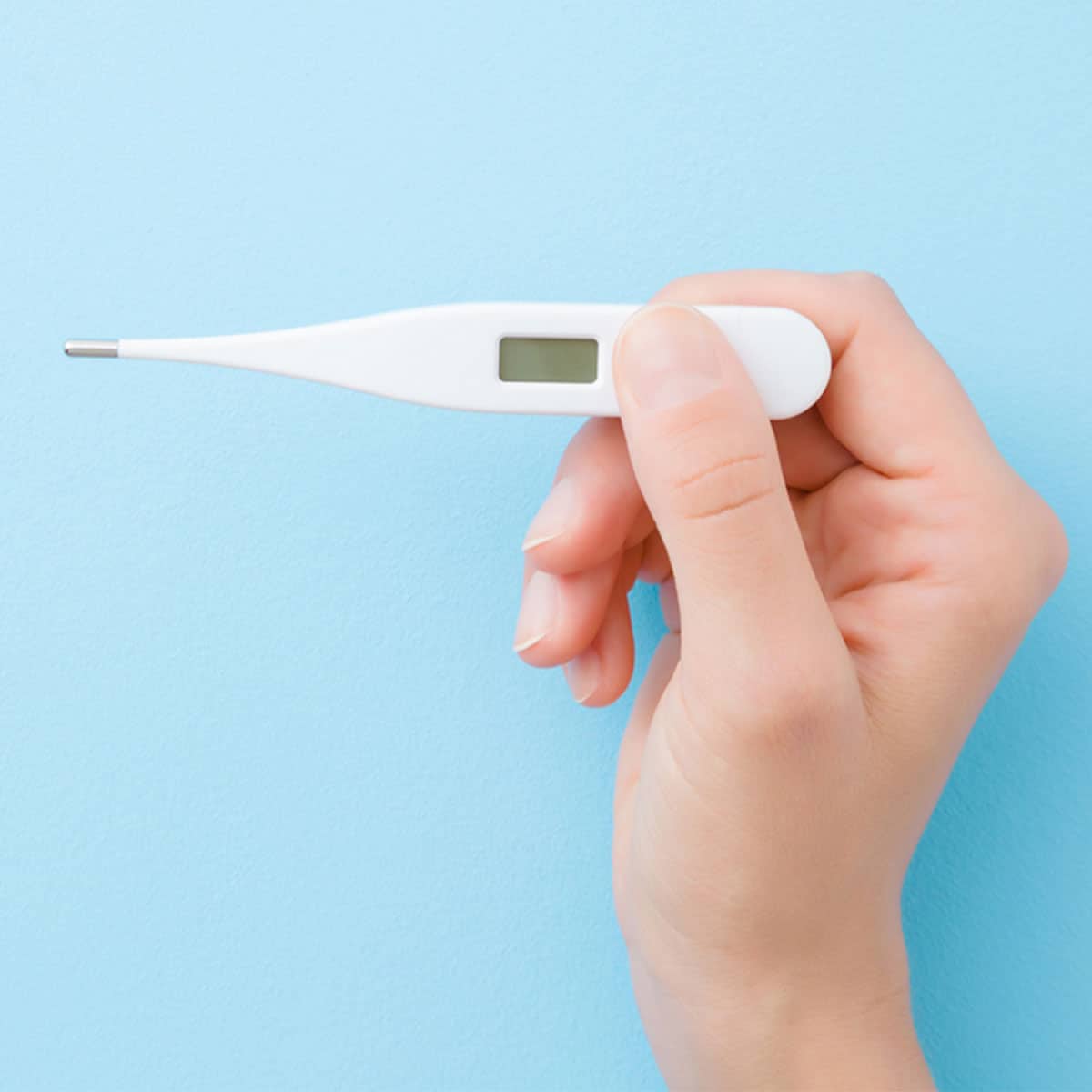 hand holding thermometer with blue background