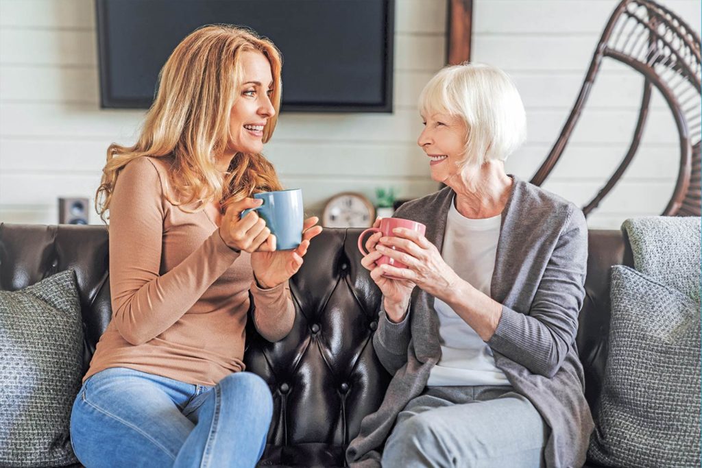 happy woman and her older mother talking over coffee