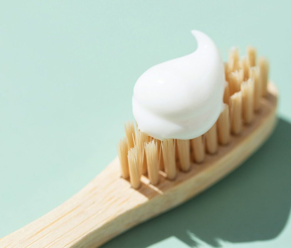 toothbrush with toothpaste on a mint colored background