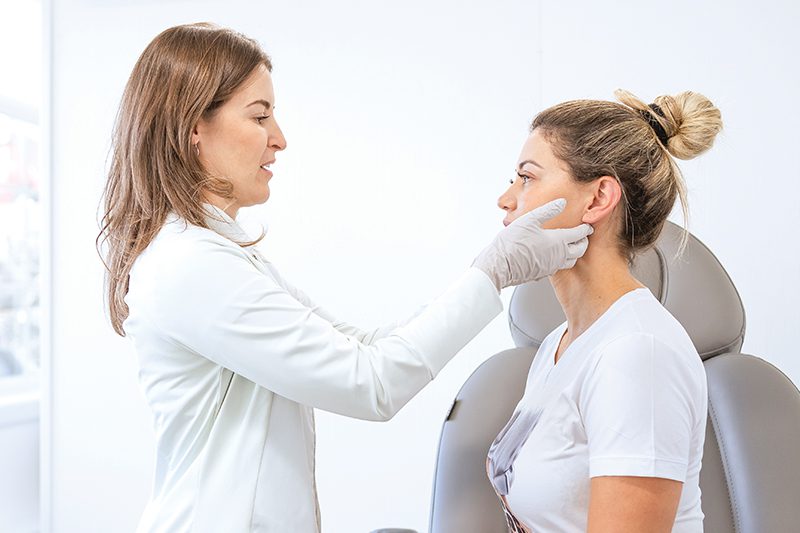 dermatologist looking at her patient's skin