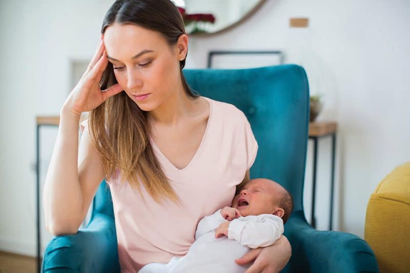 mother struggling with postpartum recovery holding her baby