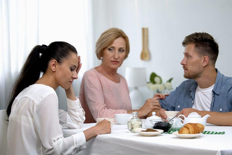 woman looking away from her angry mother-in-law and husband
