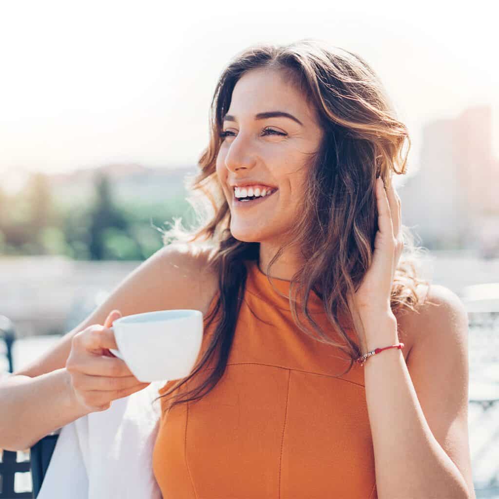 smiling woman with white teeth drinking coffee