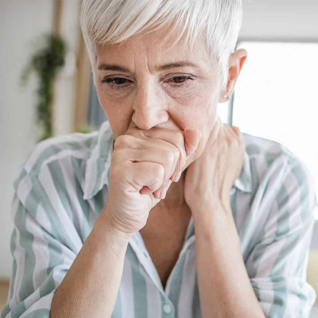 older woman coughing due to respiratory health