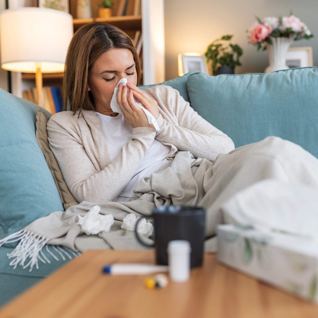 woman blowing her nose from being sick with the flu